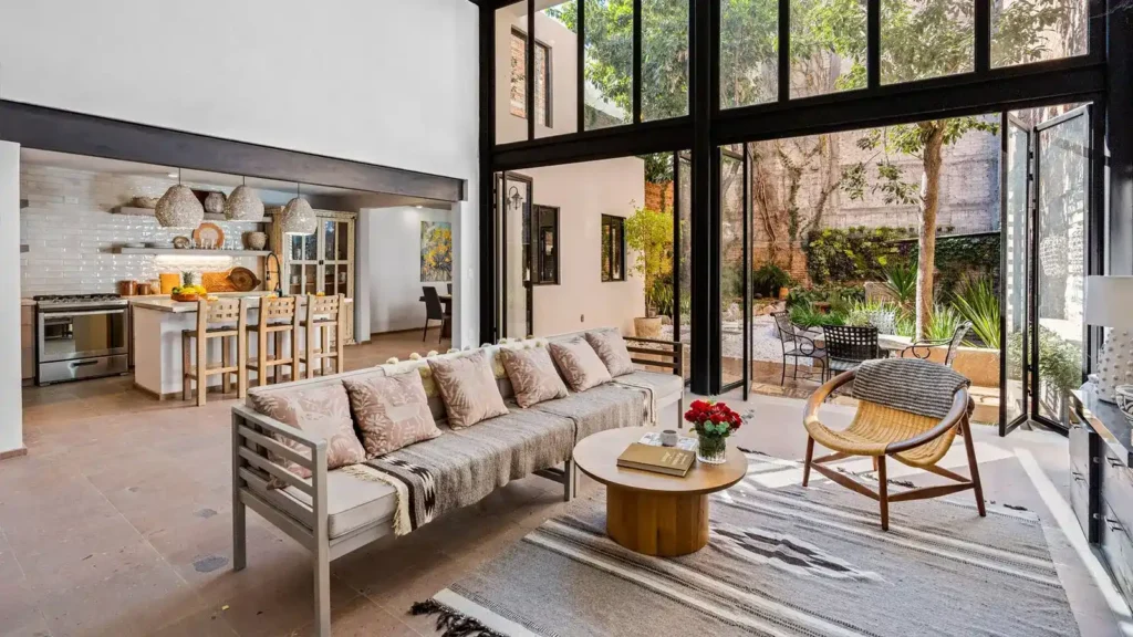 Modern luxury living room and open kitchen with floor-to-ceiling windows and garden views in San Miguel de Allende.