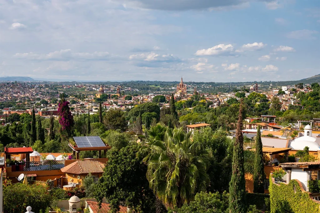 Panoramic view of San Miguel de Allende from Ojo de Agua, showcasing the Parroquia and lush hillside homes.
