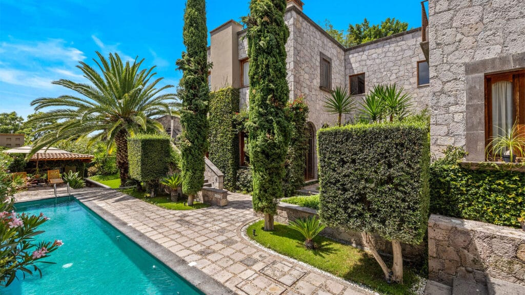 Colonial luxury home in San Miguel de Allende with stone architecture, ivy-covered walls, turquoise pool, and landscaped gardens showcasing traditional Mexican design