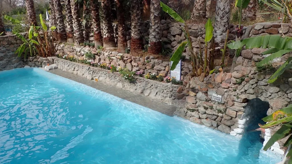 La Gruta hot springs near San Miguel de Allende featuring turquoise thermal pools surrounded by stone walls, palm trees, and tropical vegetation - popular day trip destination