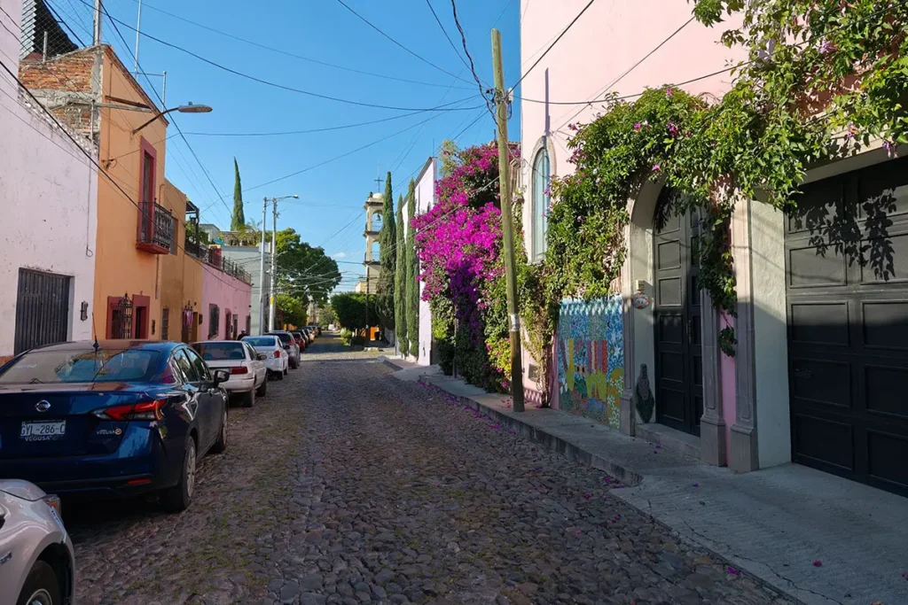 Cobblestone street with murals and bougainvillea in Guadalupe San Miguel de Allende