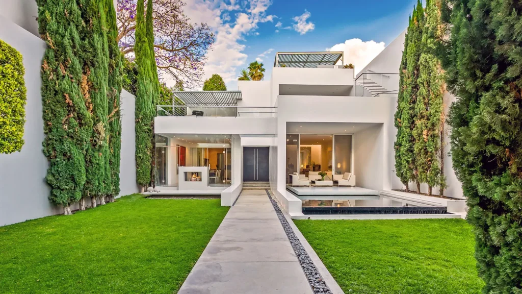Modern luxury home in San Miguel de Allende featuring contemporary white architecture, floor-to-ceiling glass walls, manicured garden, and rooftop terrace