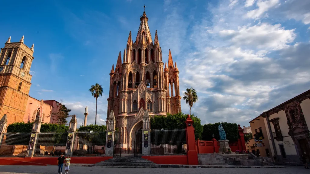 Parroquia de San Miguel Arcangel rising above the main plaza in San Miguel de Allende, Guanajuato, with its distinctive pink limestone neo-Gothic facade and colonial buildings surrounding El Jardin